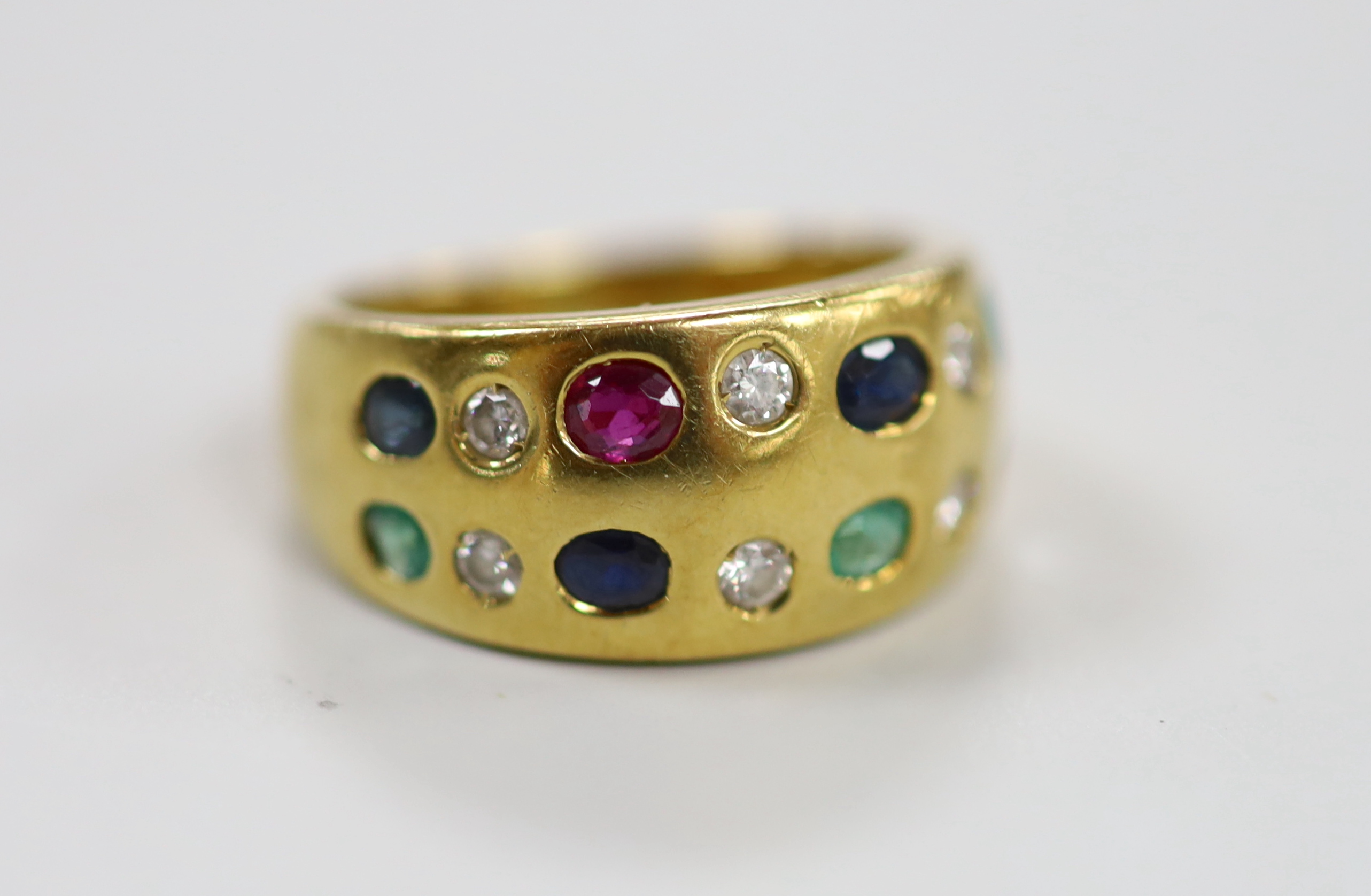 A modern 750 and gypsy set two row, ruby, emerald, sapphire and diamond half hoop ring, size K, gross weight 7.6 grams (stone missing).